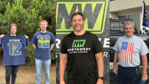 Four people showcasing custom prinited t-shirts; two holding sports-themed shirts with "PETERSON 12" and "PRO-VAC 12" designs, one wearing a "Northwest Custom Apparel" shirt, and another in a patriotic flag tee, all representing personalized apparel option