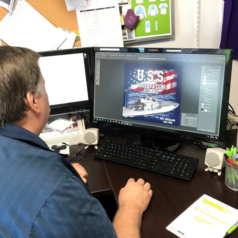 Steve Deland, our art director sitting in front of a computer screen designing a navy ship for a yearly navy reunion